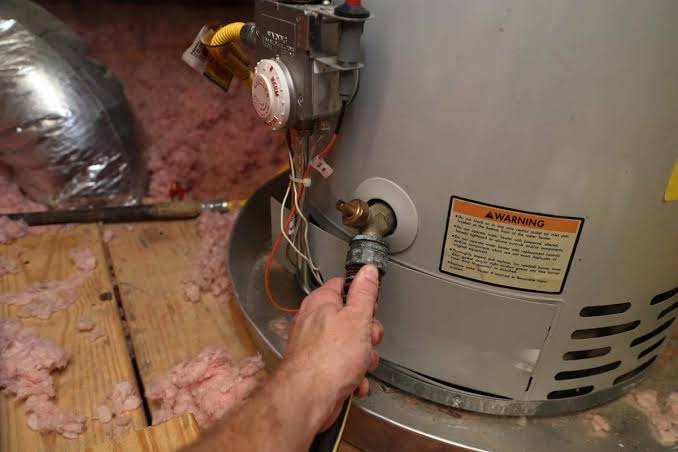Plumber flushing and draining sediment buildup from water heater tank in Punta Gorda FL